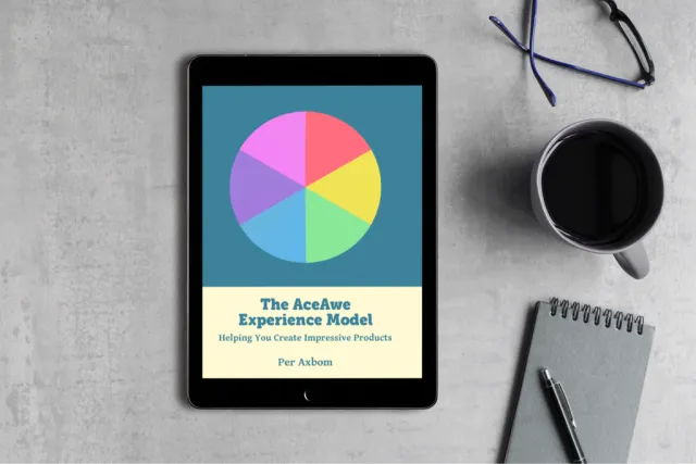 The e-book The AceAwe Experience Model – Helping You Create Impressive Products, on a tablet next to a cup of coffee, glasses and a notebook. The cover shows a circle in six colors.