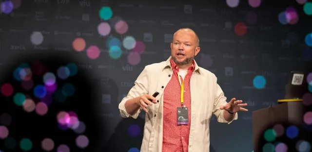 Per Axbom på scen på Front Conference, gestikulerar med en fjärrkontroll i handen.