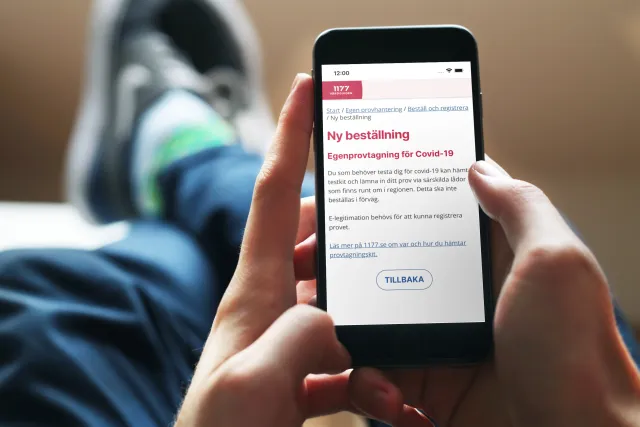Person använder egen provhantering för att beställa ett prov: En person som slappar i soffan beställer ett egentest i telefonen.