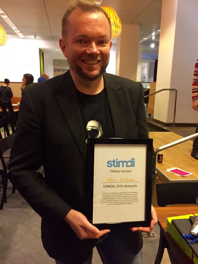 Per Axbom ler och håller sitt inramade diplom för STIMDI:s stora pris 2016.